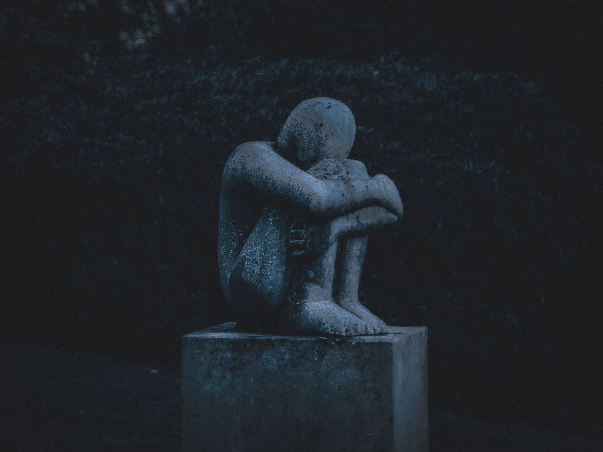 Statue sitting with knees folded and head in hands